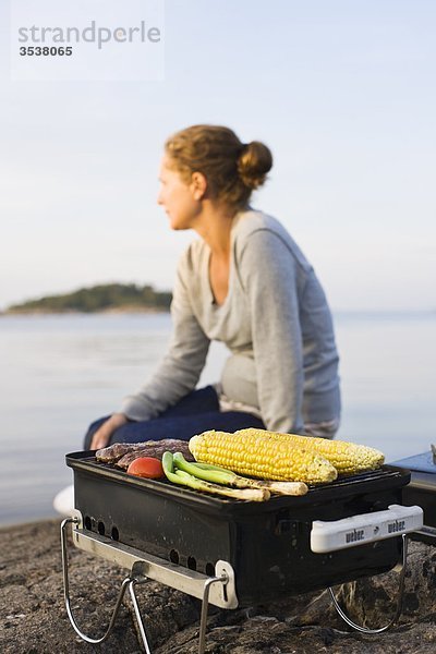 Barbecue-Grill mit Frau im Hintergrund