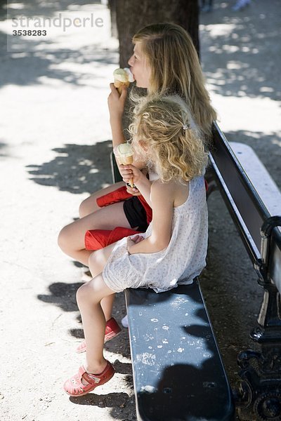 Mädchen auf Bank sitzen und Eis essen
