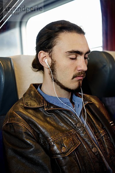 Man sitzt im Zug mit Augen geschlossen und hören Musik