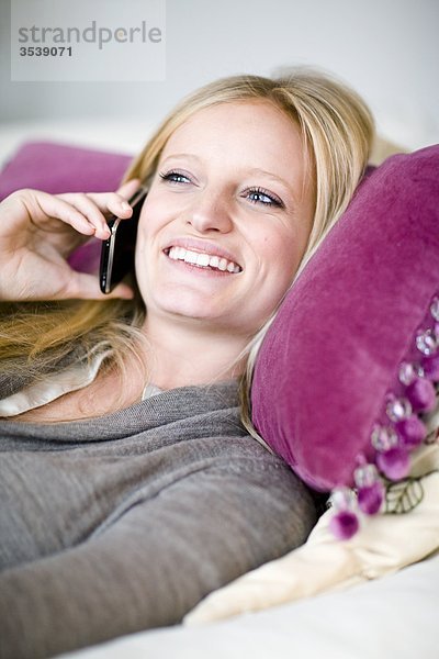 Frau auf liegen auf dem Bett und am Telefon sprechen