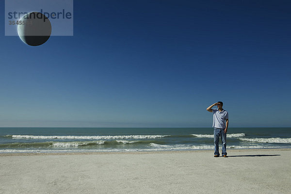 Mann am Strand beobachtet Sonnenfinsternis