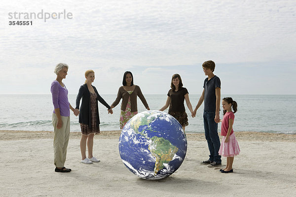 Ökologiekonzept  Gruppe von Menschen  die Händchen halten  um den Planeten Erde herumstehen