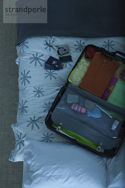Gepackter Koffer offen auf dem Bett liegend