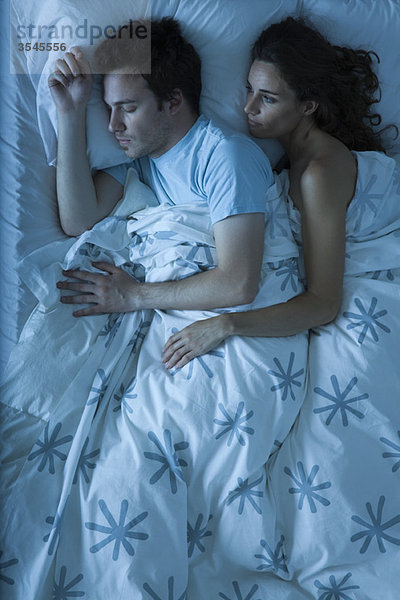 Paar im Bett  Frau umarmt den Mann  schaut ihm beim Schlafen zu.