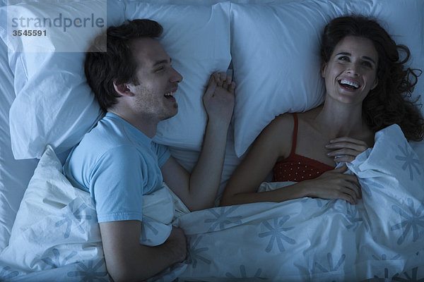 Paar im Bett liegend lachend