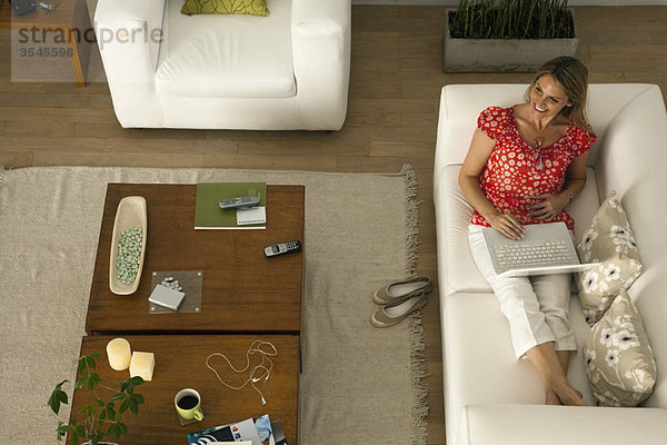 Frau entspannt sich im Wohnzimmer mit dem Laptop