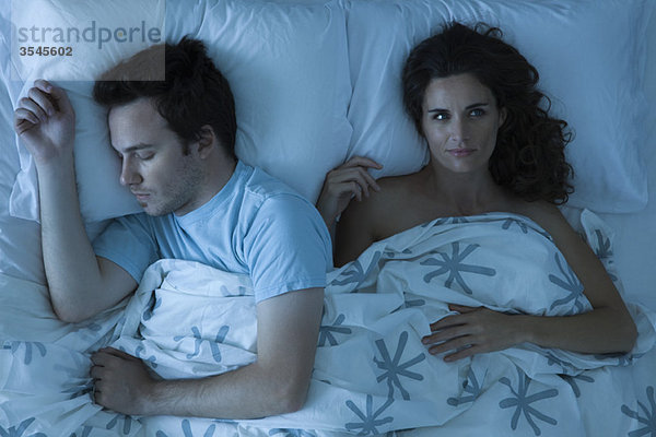 Paar im Bett liegend  Frau wach  nachdenklich wegschauend