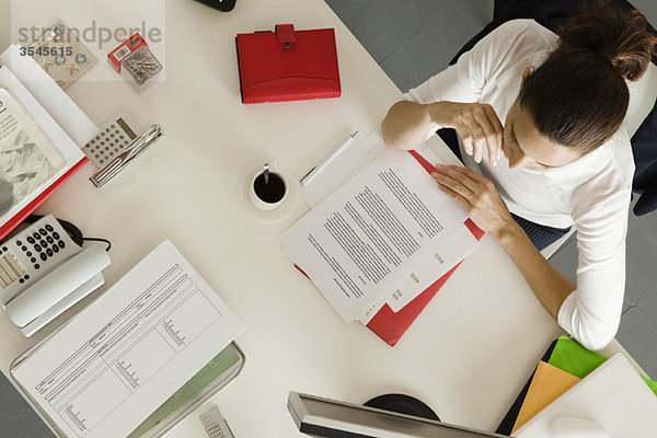 Geschäftsfrau am Schreibtisch beschäftigt mit Papierkram  Draufsicht