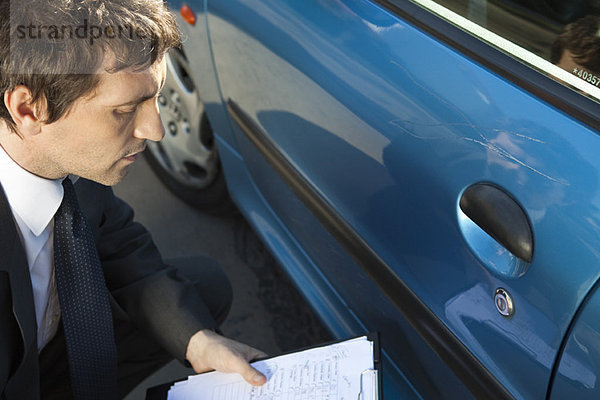 Versicherungssachverständiger bei der Untersuchung von Schäden an der Fahrzeugaußenseite