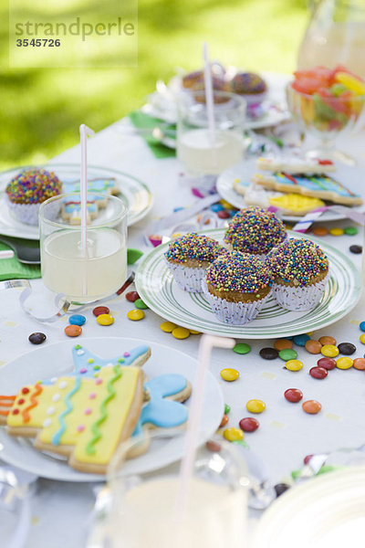 Eisgebäck und Muffins auf dem Tisch mit Streamer und Bonbons verziert