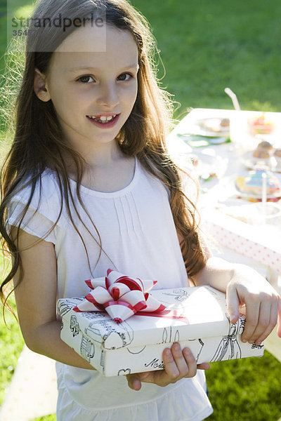 Mädchen bei Geburtstagsfeier mit verpacktem Geschenk