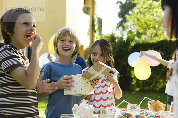 Junge Eröffnungsgeschenk und lächelt gerne bei Geburtstagsfeier