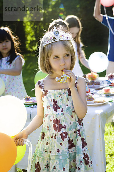 Mädchen mit Diadem und blasendem Partyhupenbläser auf der Outdoor-Party