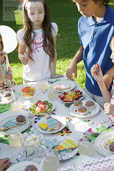 Kinder um den Süßigkeiten-Tisch bei der Geburtstagsfeier im Freien