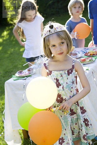 Mädchen mit Diadem und Luftballons auf der Outdoor-Party