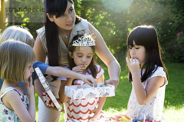 Mutter hilft Tochter offenes Geschenk bei Geburtstagsfeier