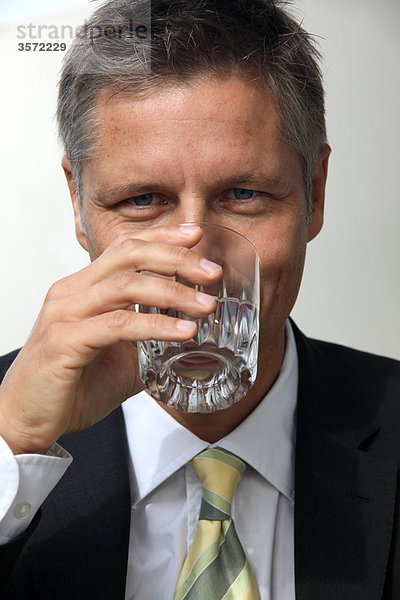 Geschäftsmann trinkt aus einem Wasserglas  Portrait