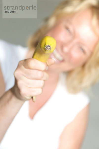 Reife Frau zielt mit einer Banane
