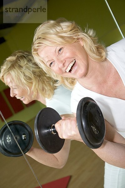 Reife Frau macht Gewichtstraining im Fitness-Studio