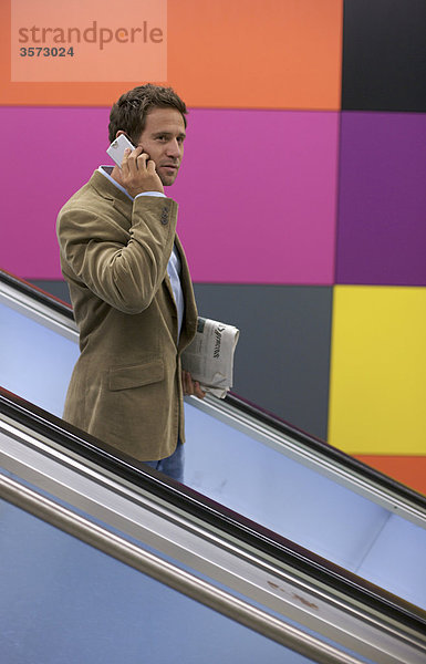 Mann telefoniert auf einer Rolltreppe