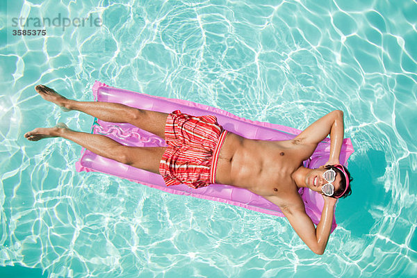 Mann auf einer aufblasbaren Matratze im Pool