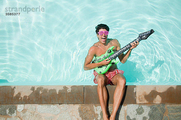 Mann im Pool mit aufblasbarer Gitarre