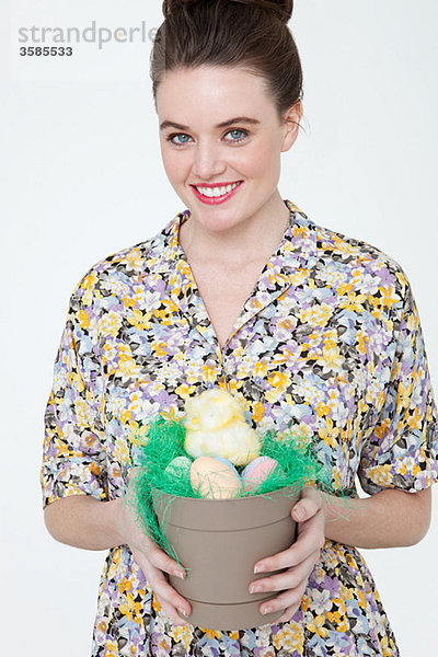 Junge Frau mit Osterküken und Eiern im Blumentopf