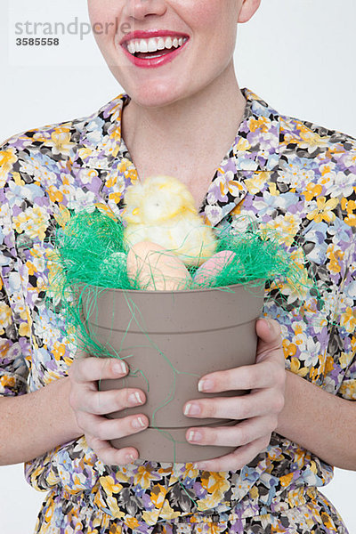 Junge Frau mit Osterküken und Eiern im Blumentopf