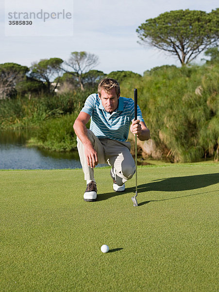 Mann spielt Golf  auf Putting Green