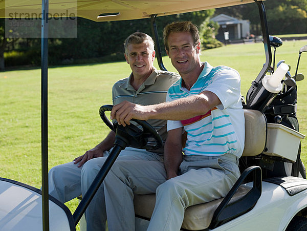 Zwei reife Männer im Golfwagen auf dem Golfplatz