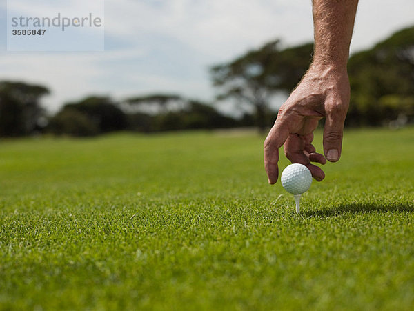 Mann spielt Golf  nimmt den Ball auf.