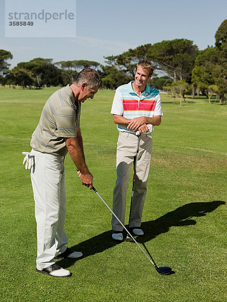 Zwei reife Männer spielen zusammen Golf.