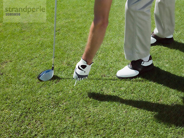 Mann spielt Golf  nimmt den Ball auf.