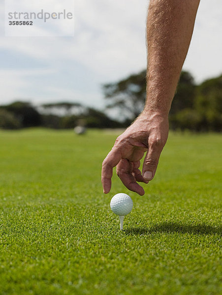 Mann spielt Golf  nimmt den Ball auf.