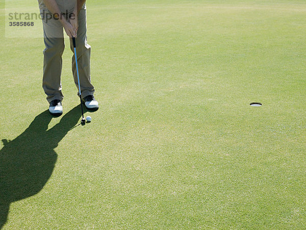 Mann spielt Golf  auf Putting Green