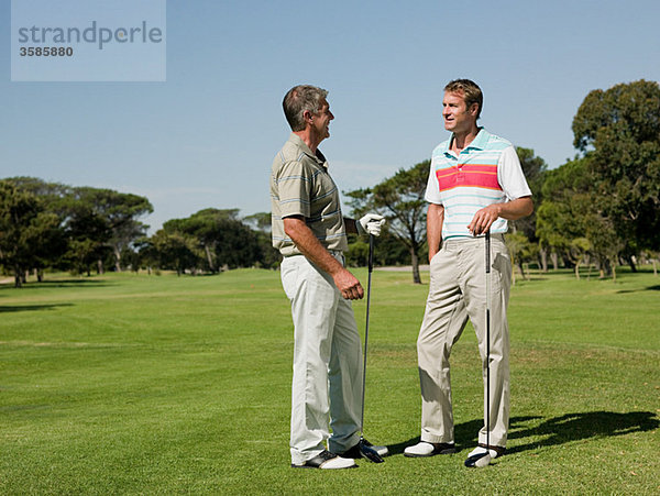 Zwei reife Männer spielen zusammen Golf.