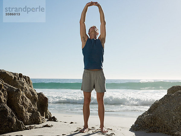 Junger Mann beim Yoga am Strand