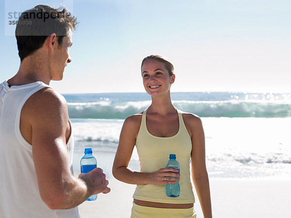 Junges Paar mit Wasserflaschen am Strand