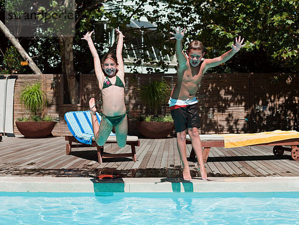 Junge und Mädchen beim Sprung ins Schwimmbad