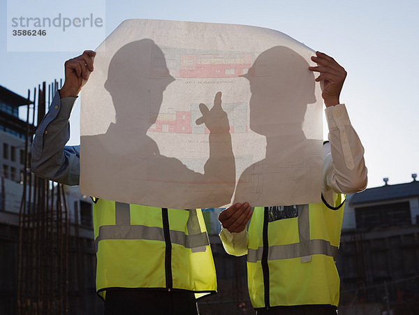 Reife Männer mit Bauplan auf der Baustelle