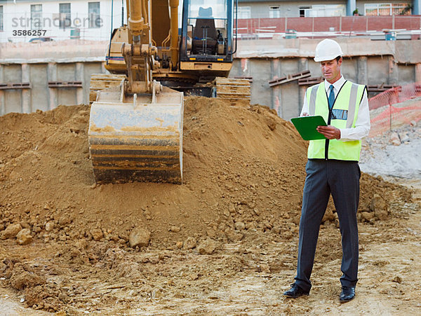 Erwachsener Mann mit Klemmbrett auf der Baustelle