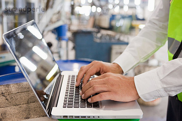 Erwachsener Mann mit Laptop in der Fabrik