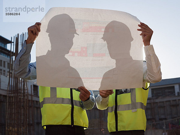 Reife Männer inspizieren Blaupausen auf der Baustelle