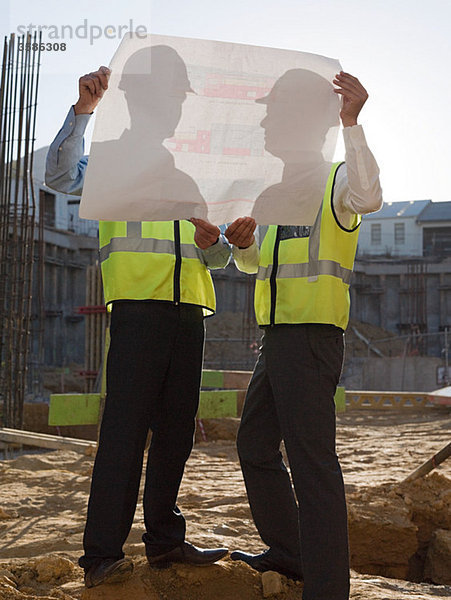 Reife Männer inspizieren Blaupausen auf der Baustelle