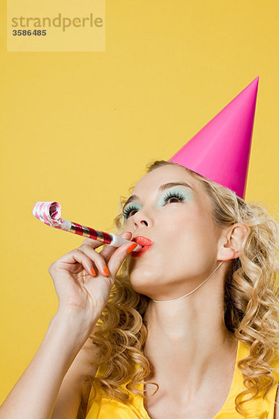 Junge Frau mit Partyhut und Partygebläse