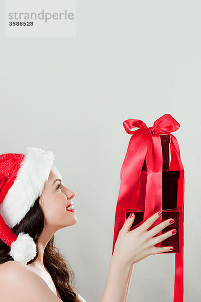 Junge brünette Frau mit Weihnachtsmütze und Weihnachtsgeschenk