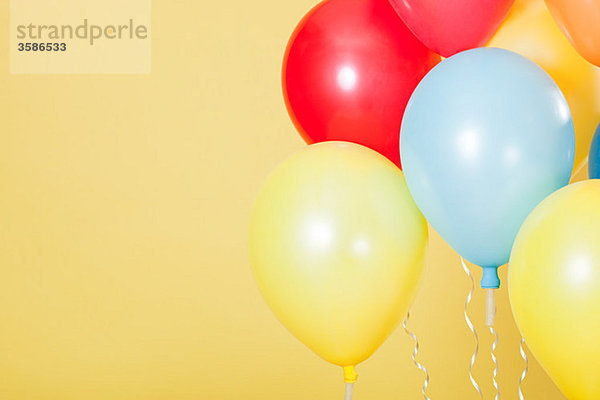 Bunte Partyballons vor gelbem Hintergrund