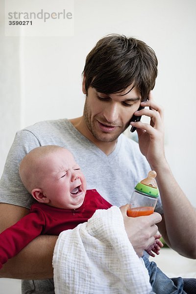 Mann mit Baby beim Telefonieren