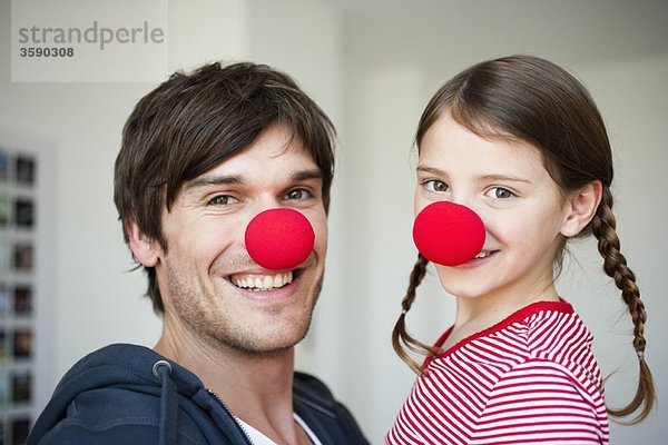 Vater und Mädchen mit roten Nasen