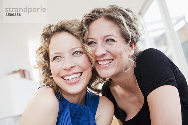Zwei Frauen von Wange zu Wange lächelnd